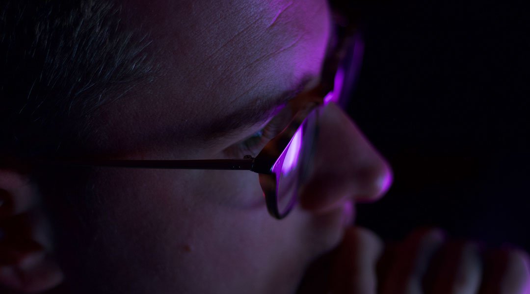 Man sitting at computer wearing blue light glasses