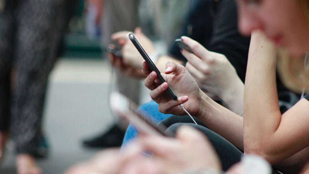 Public bench full of people using their mobile phones